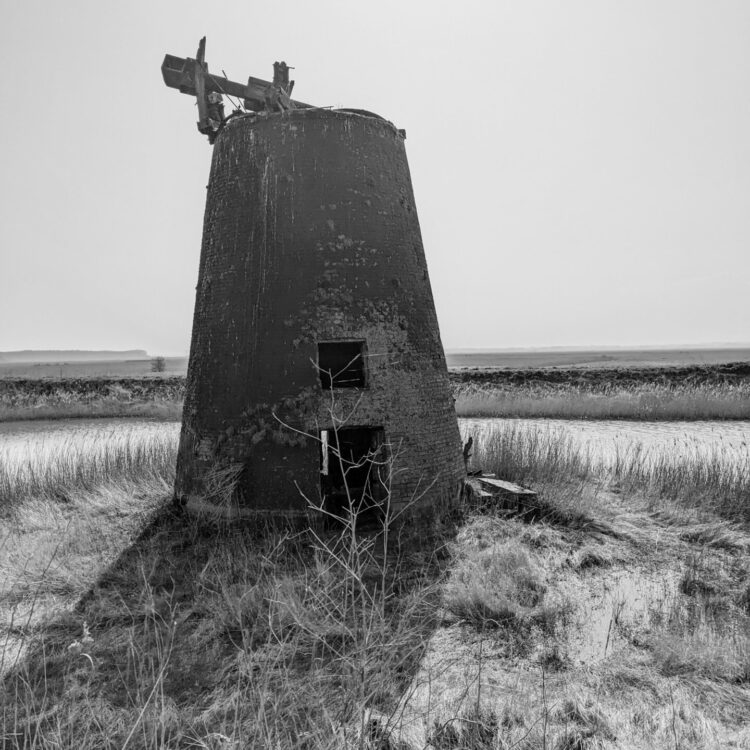 Runined Windmill with reeds surrounding. Water in the disancte